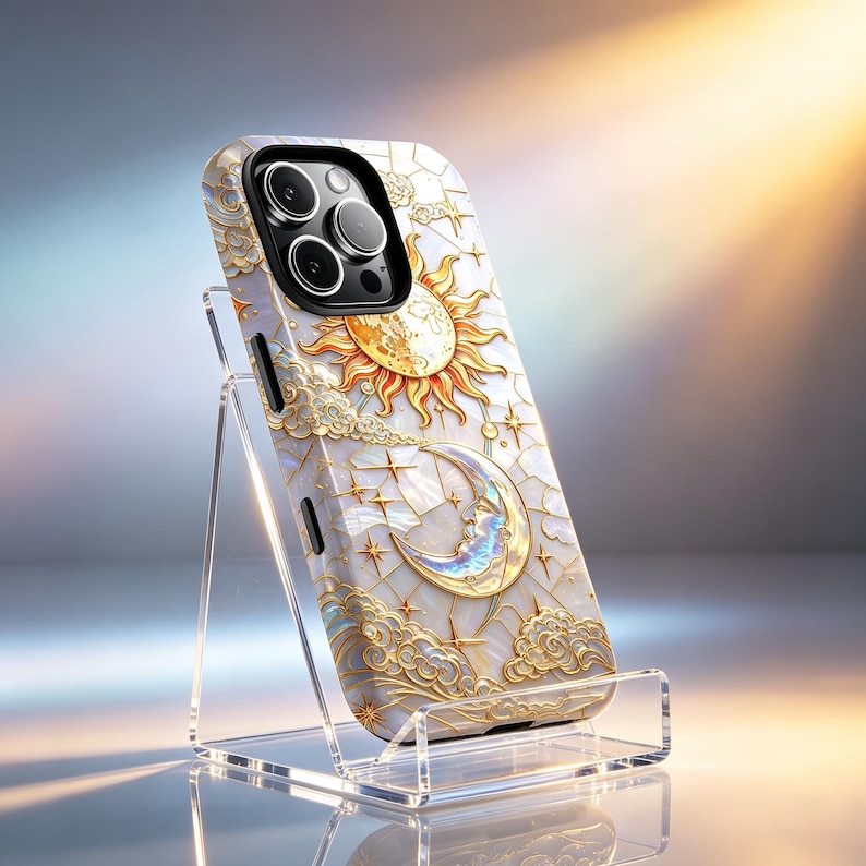 May include: A celestial-themed phone case featuring a sun, moon, and stars design. The case has a pearlescent background with gold accents. The phone case is displayed on a clear acrylic stand.