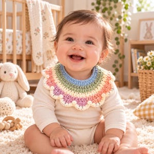 May include: A crochet baby bib featuring a scalloped edge and a multi-colored striped pattern in shades of light blue, sage green, cream, and soft pink. The bib is worn over a long-sleeved cream-colored bodysuit, showcasing a textured yarn design.