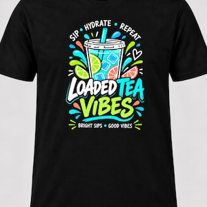 May include: A black t-shirt featuring a graphic of a plastic cup with a straw, lime and grapefruit slices, and blue liquid. The text reads "SIP HYDRATE REPEAT", "LOADED TEA VIBES", and "BRIGHT SIPS GOOD VIBES" in white, blue, and lime green lettering.