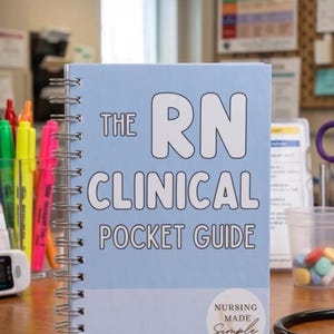 Op de afbeelding: Een lichtblauw spiraalgebonden notitieboek met de titel "THE RN CLINICAL POCKET GUIDE". De omslag heeft witte tekst en een cirkelvormig logo met de tekst "NURSING MADE Simple". Diverse gekleurde markers en medische apparatuur zijn zichtbaar.