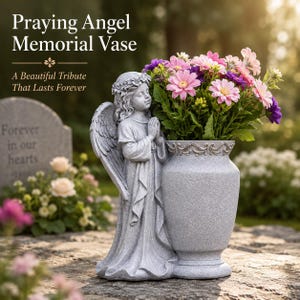 May include: A gray stone-textured memorial vase featuring a sculpted angel with folded hands and a floral wreath on its head. The vase is attached to the side of the angel figure and is filled with a bouquet of pink, purple, and white flowers.