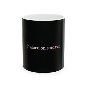 Könnte beinhalten: Eine schwarze Keramik-Kaffeetasse mit weißem Innenraum. Auf der Tasse steht in hellrosa Schrift der Text "Trained on sarcasm". Die Tasse ist zylindrisch und hat einen Standardgriff.