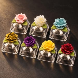May include: Seven decorative rose ornaments, each featuring a single rose in a different color—pink, white, light blue, gold, purple, yellow, and red—mounted on a clear, square acrylic base with green leaves and a small white ribbon bow.