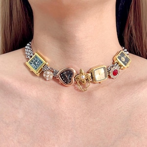 Può includere: Una collana unica con una varietà di quadranti di orologi vintage in tonalità oro e argento. La collana include quadranti quadrati, a cuore e rotondi, alcuni con pietre preziose e dettagli di perle. La catena è a maglia a catena argento e oro.