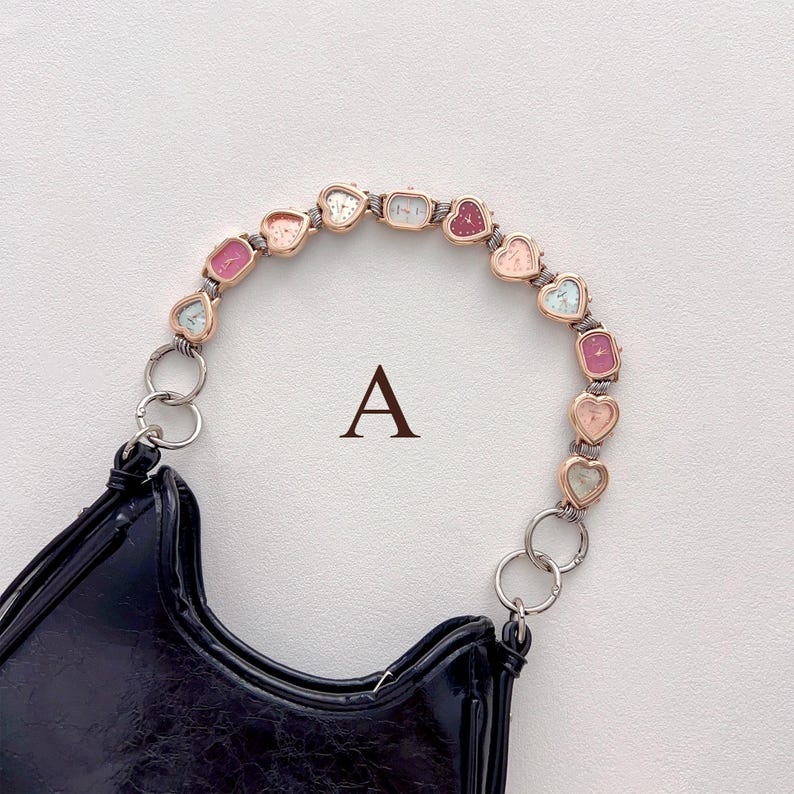 May include: Black patent leather handbag with a unique handle composed of heart-shaped watch faces in various pastel colors. The letter "A" is printed on the background.