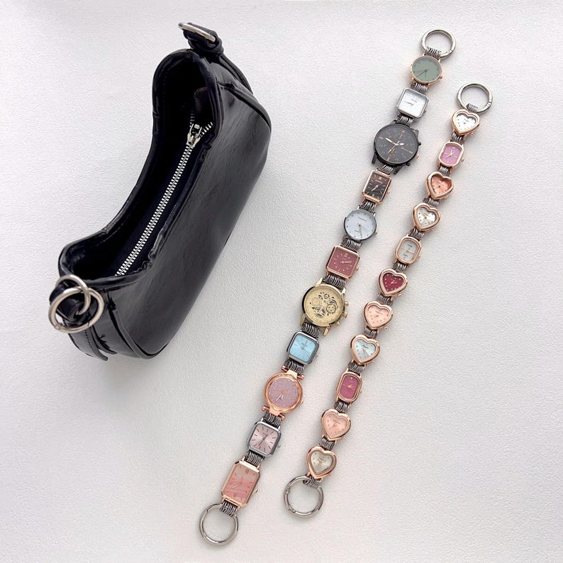 May include: A black, glossy, small handbag with a silver zipper and hardware, next to two watch straps. One strap features a variety of square and round watch faces in different colors. The other strap has heart-shaped watch faces.