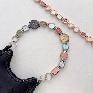 May include: A black patent leather handbag with a unique strap made of various small watches in different shapes and colors. A second strap with heart-shaped watch faces is also visible.