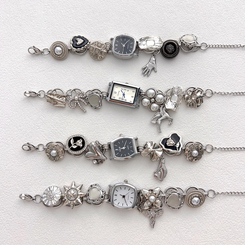 May include: Four silver charm bracelets with various charms, including small watches, hearts, flowers, and other decorative elements. The bracelets are displayed on a white surface, showcasing the intricate details of each piece.