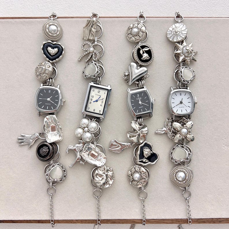 May include: Four silver charm bracelets with various embellishments, including small watches, hearts, bows, and floral designs. Each bracelet has a different combination of charms and a delicate chain.