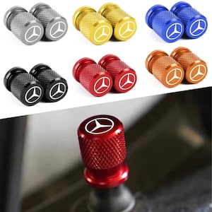 May include: A collection of colorful, textured metal valve stem caps. The caps are available in silver, gold, blue, black, red, and orange. Each cap features a white logo. The caps are designed for automotive use.