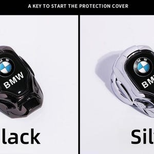 May include: Black and silver BMW key fob covers. Each cover features the BMW logo in the center. The black cover is on the left, and the silver cover is on the right. The text "Black" and "Silver" are below each cover.