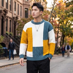Può includere: Un maglione a maniche lunghe in maglia a trecce con un motivo a blocchi di colore composto da pannelli giallo senape, bianco e verde acqua tenue. Il capo presenta girocollo, polsini e orlo a coste, con una trama a trecce verticali costante.