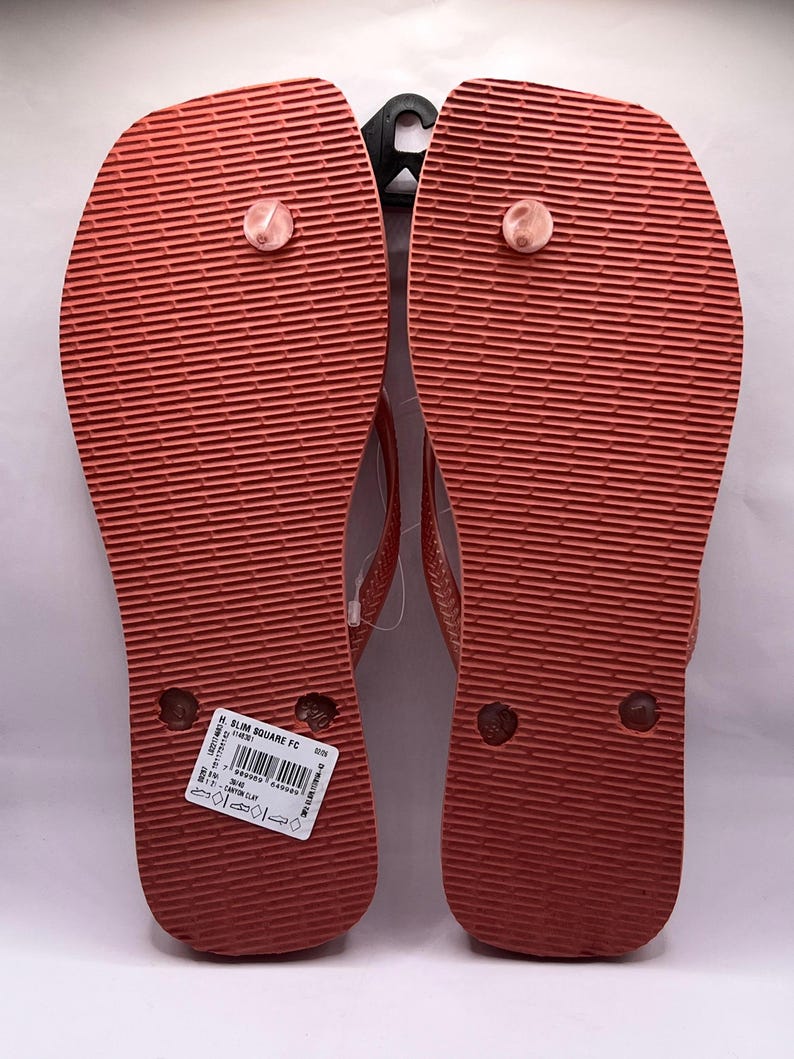 K&ouml;nnte beinhalten: Paar korallenfarbene Flip-Flops mit strukturierten Sohlen. Die Flip-Flops haben ein schlichtes Design mit einem Zehenriemen. Die Sohlen sind einfarbig korallenfarben und die Riemen sind in einem helleren Korallton gehalten. Die Flip-Flops sind neu und ungetragen.