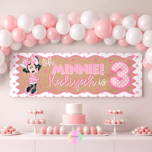 May include: A party banner featuring a tan background with pink polka dots, a Minnie Mouse illustration, and the text Oh MINNIE! Kaliyah is 3. The banner is framed by a white scalloped border and surrounded by a balloon arch of pink and white balloons.