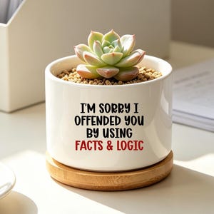 May include: A white cylindrical ceramic planter with a bamboo saucer base containing a small green succulent. The planter features black text that reads I'M SORRY I OFFENDED YOU BY USING and red text that reads FACTS & LOGIC on the front side.