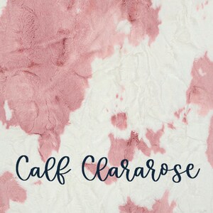 May include: A plush, textured blanket with a white background and large, irregular patches of dusty rose. The words "Calf Clararose" are written in a cursive font across the bottom.