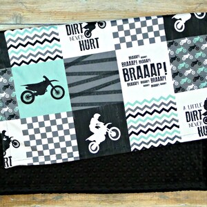 May include: A black and white checkered fabric with a green and black chevron pattern. The fabric has a motocross theme with images of dirt bikes and the text "Dirt Never Hurt" and "Braaap!"
