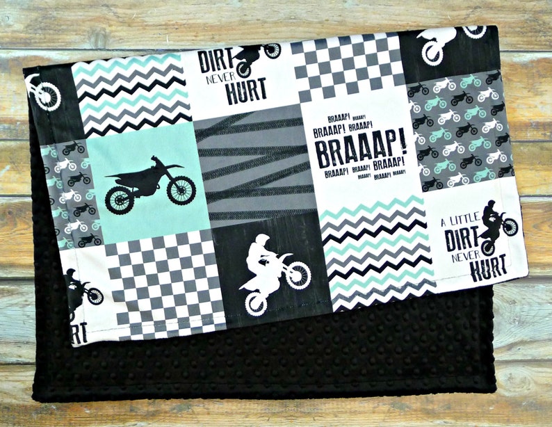 May include: A black and white checkered fabric with a green and black chevron pattern. The fabric has a motocross theme with images of dirt bikes and the text "Dirt Never Hurt" and "Braaap!"