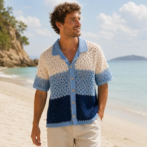 May include: A short-sleeve button-down shirt featuring a crochet knit pattern. The shirt displays a horizontal color-blocked design transitioning from cream at the top to light blue in the middle and dark navy blue at the bottom hem.