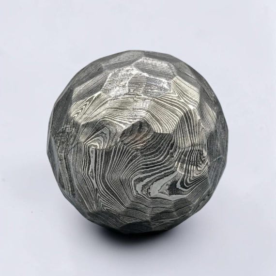 Hammered Damascus steel sphere that doubles as a desk paperweight, fidget object, and a genuine conversation piece — the kind of thing you pick up and can't put down.