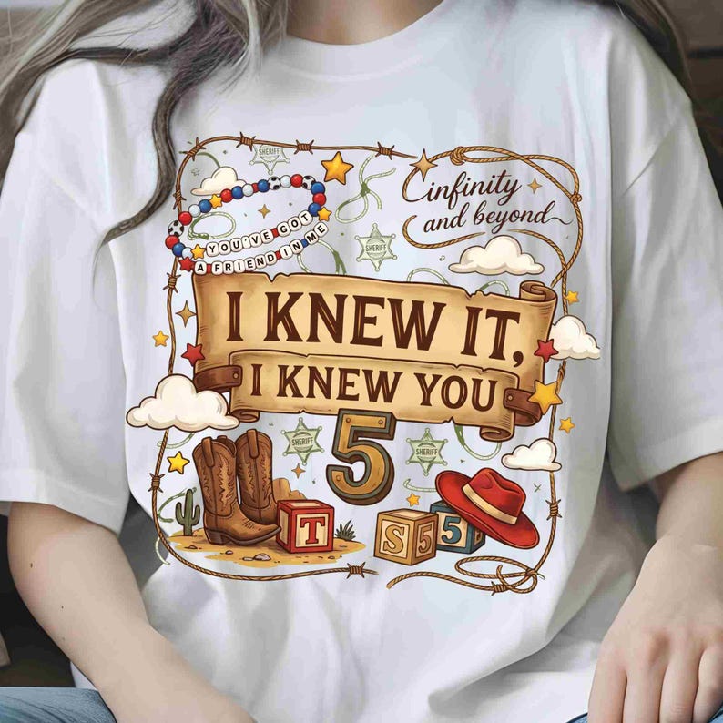 May include: A white t-shirt featuring a graphic print with a brown scroll banner that reads I KNEW IT, I KNEW YOU, the number 5, and the text Cinfinity and beyond. The design includes cowboy boots, a red hat, alphabet blocks, and sheriff stars.