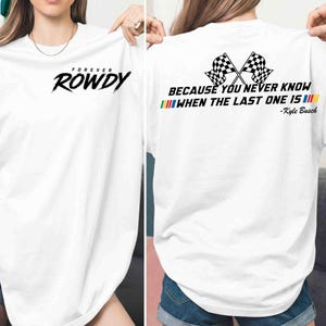 May include: White t-shirt with the text "FOREVER ROWDY" on the front in black. The back of the shirt features two crossed checkered flags and the quote "BECAUSE YOU NEVER KNOW WHEN THE LAST ONE IS" with the name "-Kyle Busch".