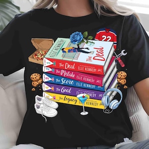 May include: Black t-shirt with a design featuring books by Elle Kennedy, including "The Deal" and "The Mistake". The image also shows a pizza box, cookies, trainers, a cocktail, and a hockey jersey. The design is colourful and eye-catching.