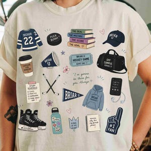 Puede incluir: Camiseta color crema con varios gr&aacute;ficos tem&aacute;ticos universitarios. Incluye una camiseta de hockey, un disco, libros, una gorra, una bolsa de lona, un tel&eacute;fono, una botella de agua y un dedo de espuma. El texto incluye "Briar U", "Caffeine for Survival" y "#1 Fan".