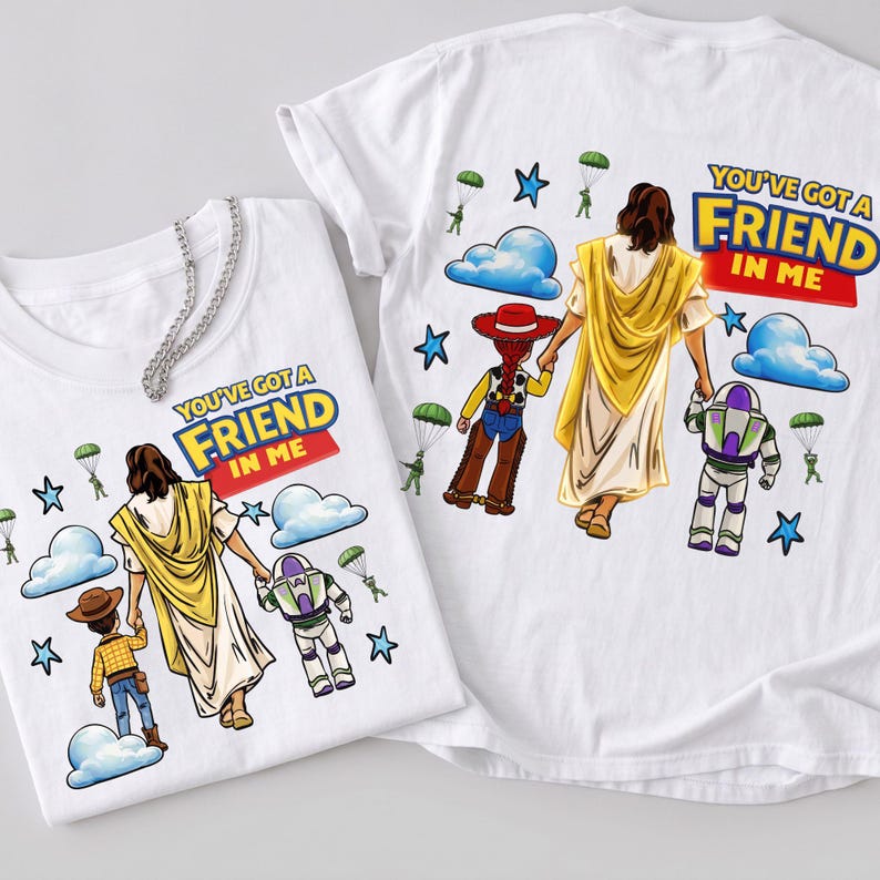 May include: Two white t-shirts with the phrase "YOU'VE GOT A FRIEND IN ME" printed on them. The shirts feature a graphic of a figure in a yellow robe holding hands with a cartoon cowboy and a space ranger. Blue clouds, stars, and parachutes are also included.