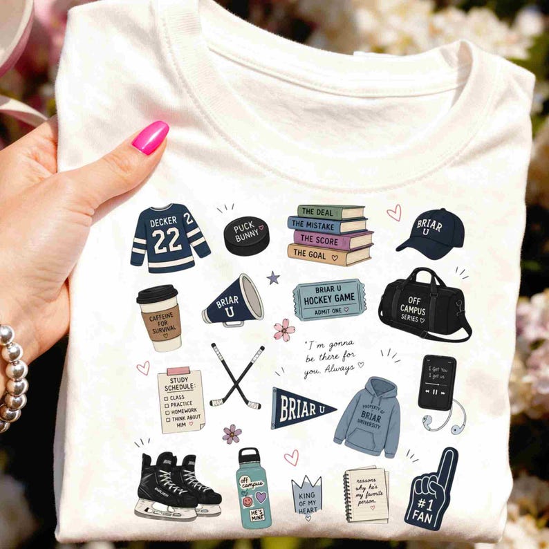 Puede incluir: Camiseta blanca con varias ilustraciones gr&aacute;ficas, incluyendo una camiseta de hockey, un disco, libros, un gorro, una taza de caf&eacute;, palos de hockey, una botella de agua y un dedo de espuma. La camiseta tiene el texto "Briar U" y otras frases.