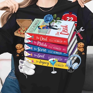 May include: Black t-shirt with a design featuring a stack of books titled "The Deal", "The Mistake", "The Score", "The Goal", and "The Legacy" by Elle Kennedy. The design includes a pizza box, cookies, trainers, a cocktail, and a hockey jersey.