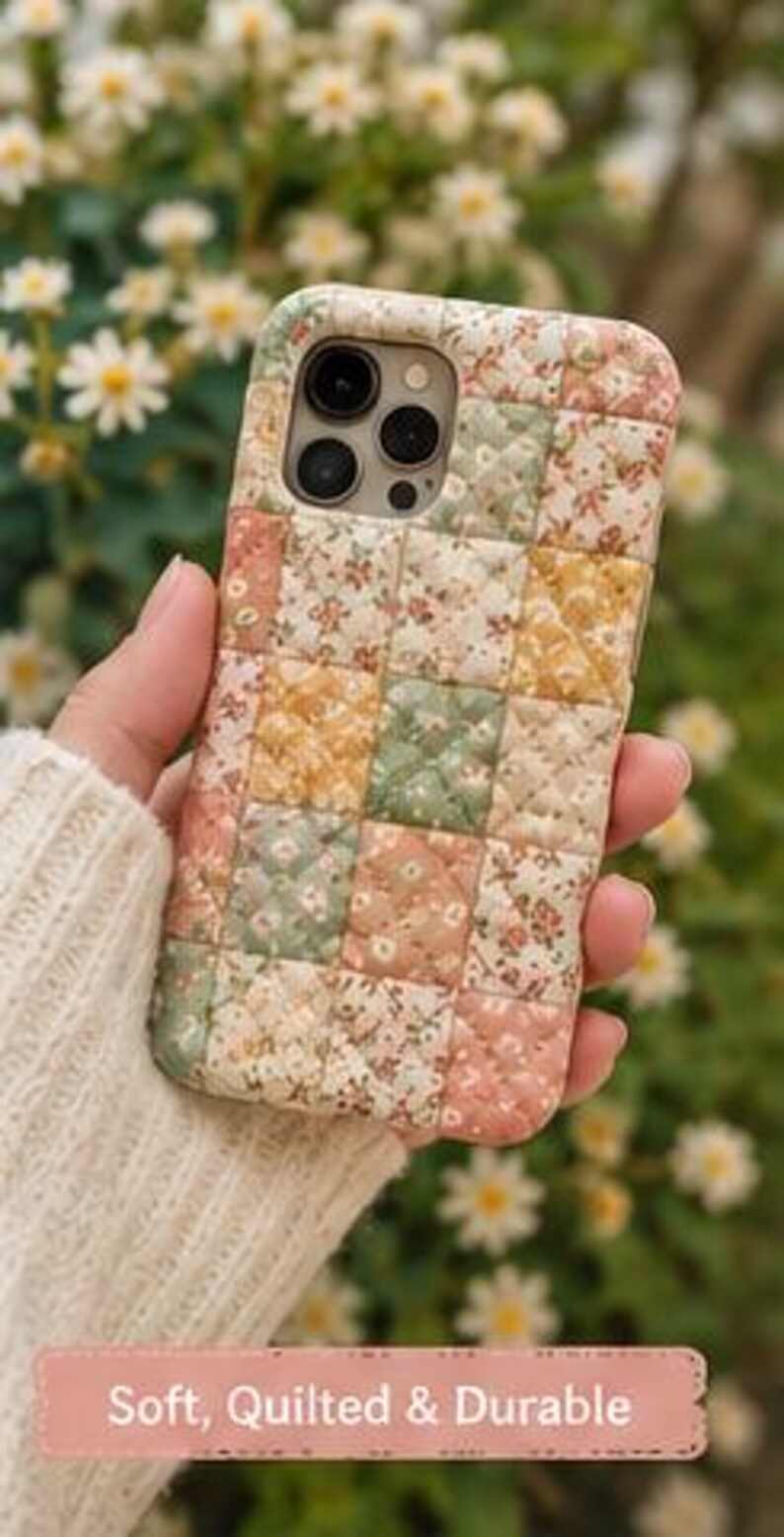 May include: A quilted phone case featuring a patchwork design of floral patterns in shades of pink, yellow, and green. The case has a square-stitched texture and includes the text "Soft, Quilted & Durable" printed on a pink rectangular banner at the bottom.