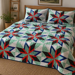 Könnte beinhalten: Eine gesteppte Tagesdecke und zwei passende Kissenbezüge mit einem sich wiederholenden geometrischen Sternmuster. Das Design kombiniert leuchtendes Rot, tiefes Blau, Schwarz und Mintgrün auf einem weißen Hintergrund mit einer dezenten Sprenkelung.