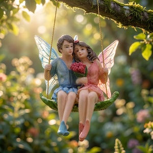 May include: A resin fairy couple figurine on a swing. The male fairy is in blue, the female in pink, both with wings. They hold red flowers. The swing is green, suspended from a tree branch. The background is a blurred garden scene.