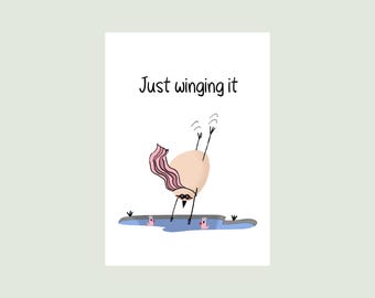 May include: A white greeting card featuring a cartoon illustration of a tan, egg-shaped character with a pink cape and black mask diving into a small blue pond. The text Just winging it is printed in black above the character, with two small pink birds.