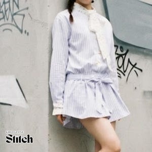 Puede incluir: Un vestido camisero de manga larga con rayas verticales en azul claro y blanco, con cuello alto y corbata de encaje blanco, puños de encaje y un cinturón de tela a juego que se ata a la cintura. La prenda tiene una falda acampanada y botones.
