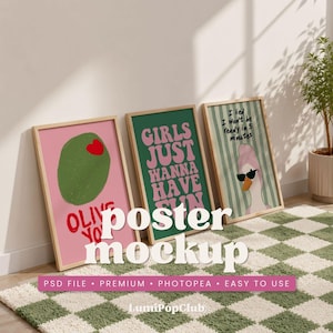 May include: Three framed posters leaning against a wall. The posters have a pink, green, and striped background. The pink poster has an olive with a heart. The green poster says "Girls Just Wanna Have Fun". The striped poster has a duck with sunglasses.