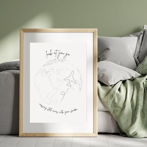 May include: A framed print with a minimalist design. The artwork features a line drawing of a globe with an airplane and a dotted flight path. The text reads "look at you go, crossing state lines with your shadow."