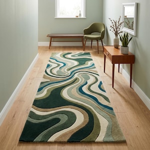 Peut inclure: Un tapis rectangulaire orné d'un motif ondulé fluide dans des tons de vert foncé, vert sauge, bleu sarcelle et crème. Le tapis présente une surface touffetée texturée avec des hauteurs de poils variables créant un effet tridimensionnel.