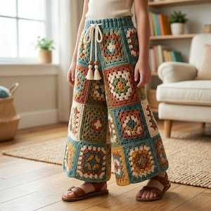 Pode incluir: Calças palazzo de crochê com um design de patchwork. As calças apresentam uma cintura com cordão e uma mistura de cores, incluindo verde-azulado, castanho, creme e verde. As calças são combinadas com sandálias de couro castanho.