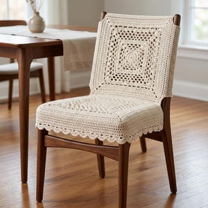 May include: A wooden dining chair with a cream-colored, crocheted seat cover and backrest. The cover features a square design with a central circular motif and a scalloped edge. The chair is part of a dining set.