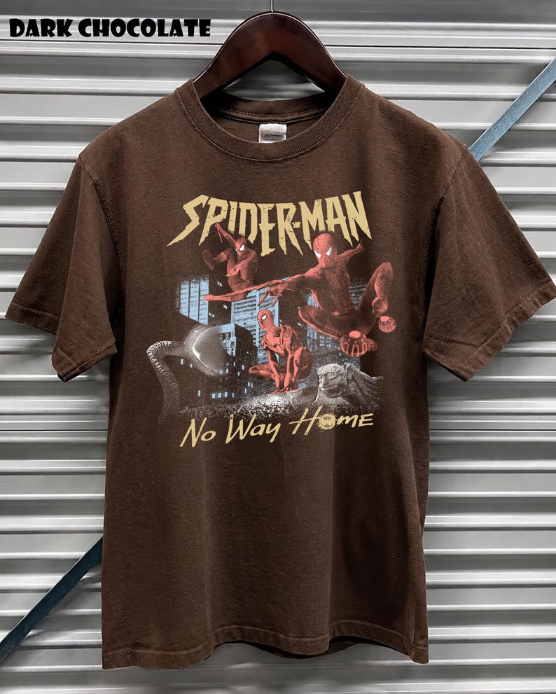 Może przedstawiać: Ciemnobrązowy t-shirt w kolorze gorzkiej czekolady z grafiką Spider-Mana. Projekt zawiera napis "SPIDER-MAN" złotymi literami oraz frazę "No Way Home". Grafika przedstawia Spider-Mana w akcji na tle miejskiego krajobrazu.