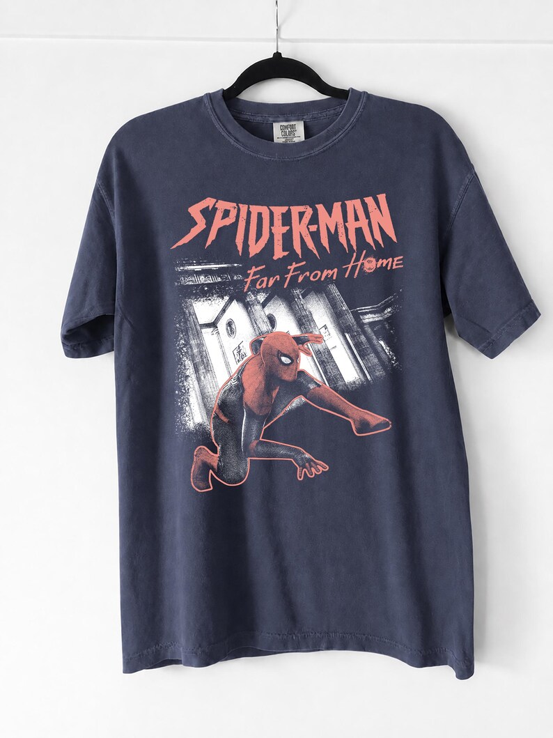 K&ouml;nnte beinhalten: Marineblaues T-Shirt mit einem Spider-Man-Motiv aus dem Film "Far From Home." Die Grafik zeigt Spider-Man in einer dynamischen Pose vor einer Stadtkulisse. Der Text "SPIDER-MAN Far From Home" ist rot gedruckt.