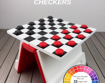 May include: A white and black draughts board game titled PLAYBOOK'D CHECKERS, featuring red and black circular game pieces. The board is supported by a white and red folding stand. A circular colour wheel graphic displays 33 unique colour choices.
