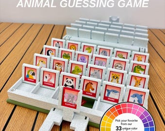 May include: A grey plastic animal guessing game board with multiple upright tiles featuring colourful illustrations of animals like an elephant, shark, and horse. The text ZOO ARE YOU? ANIMAL GUESSING GAME appears above, and a colour wheel graphic is included.
