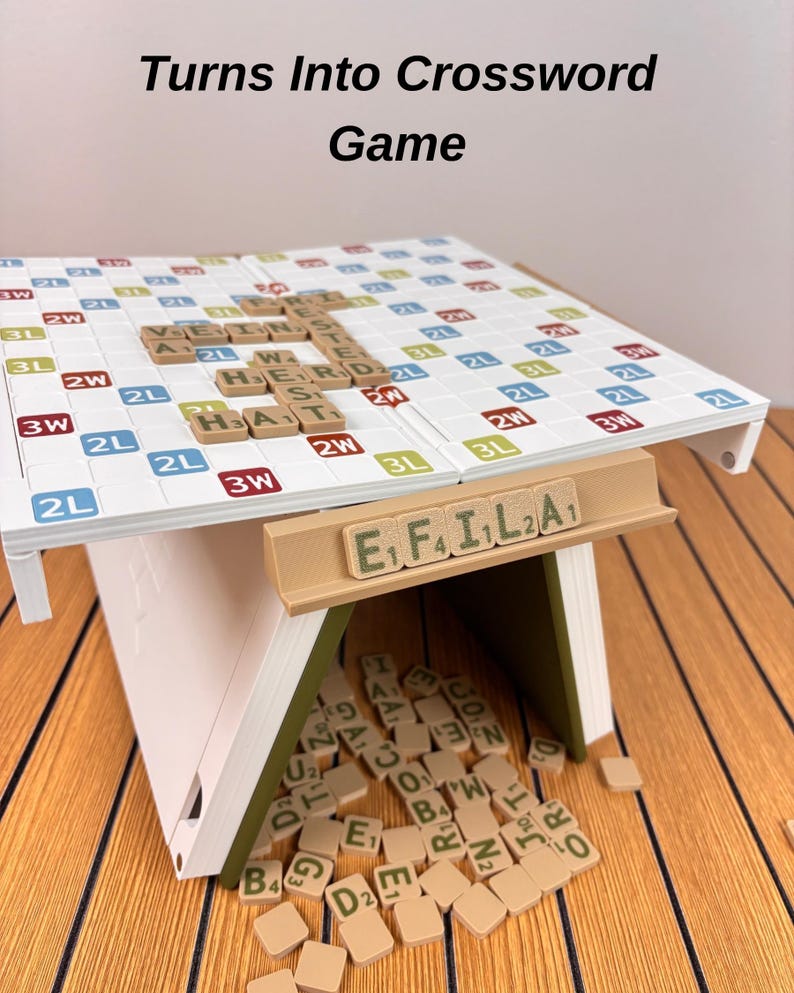 May include: A white and olive green folding board game with a grid surface featuring letter tiles spelling words like VEIN, HERD, and HAT. A tan tile rack displays the letters E, F, I, L, A, and a pile of loose letter tiles sits underneath.