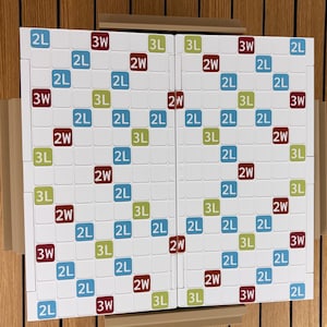 May include: A white word game board featuring a grid of squares with colored markings. The board includes blue squares labeled 2L, green squares labeled 3L, and dark red squares labeled 2W and 3W, arranged in a symmetrical pattern across two halves.