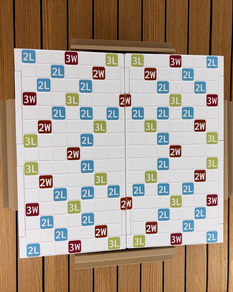 May include: A white word game board featuring a grid of squares with colored markings. The board includes blue squares labeled 2L, green squares labeled 3L, and dark red squares labeled 2W and 3W, arranged in a symmetrical pattern across two halves.