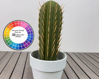 May include: A green cactus-shaped toothpick holder in a light grey speckled pot. The text CACTUS TOOTHPICK HOLDER appears at the top. A circular colour wheel graphic is present with the text Pick your favourite from our 33 unique colour choices!