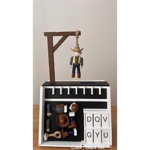 May include: A black and white cowboy-themed game set. The set includes a miniature gallows with a cowboy figure, along with various game pieces and letter tiles. The color of the set is black.